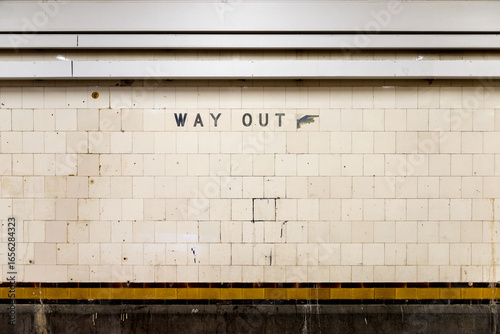 Old tiled wall with a weathered 'Way Out' sign in an underground train station