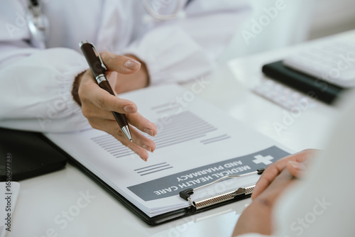 A doctor consults with a patient in a healthcare office, reviewing documents and providing medical advice, diagnosis, and treatment during a professional hospital or clinic appointment.