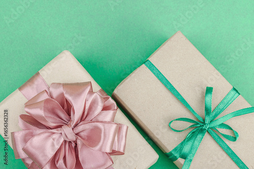 Eco-friendly gift boxes wrapped in kraft paper and decorated with satin ribbons on green background