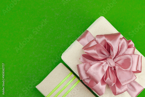 Eco-friendly gift boxes wrapped in kraft paper and decorated with satin ribbons on green background