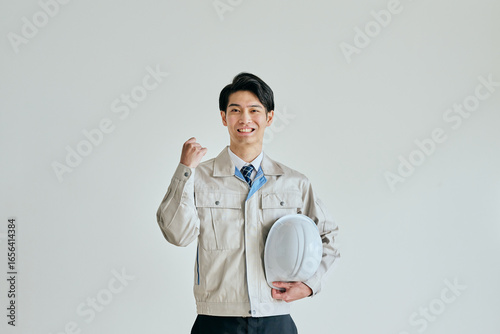 фотографія ガッツポーズをする作業服姿の若い男性