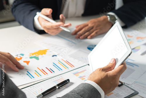 businessman holds a pen while clarifying and discussing business information at the office table, providing clear insights during  professional meeting. tablet mock up for use