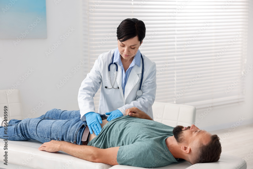 Fototapeta premium Gastroenterologist examining patient with stomach pain in clinic