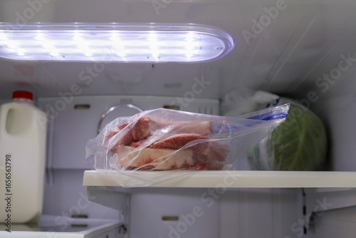 A bag of frozen pork chops thawing in a refrigerator