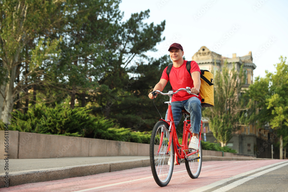 Obraz premium Courier with thermo bag riding bicycle outdoors, space for text. Food delivery service
