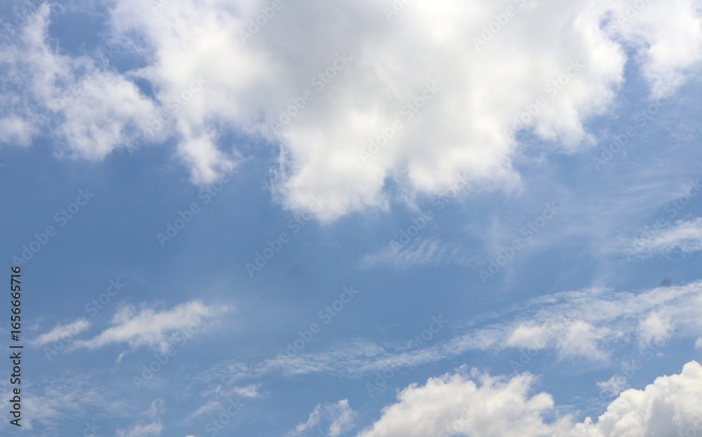 Fototapeta premium Bright blue sky with soft, fluffy white clouds drifting peacefully, creating a serene and refreshing view of nature’s beauty. Suitable for nature and simple background.