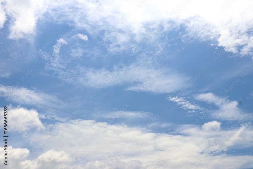 Fototapeta premium Bright blue sky with soft, fluffy white clouds drifting peacefully, creating a serene and refreshing view of nature’s beauty. Suitable for nature and simple background.