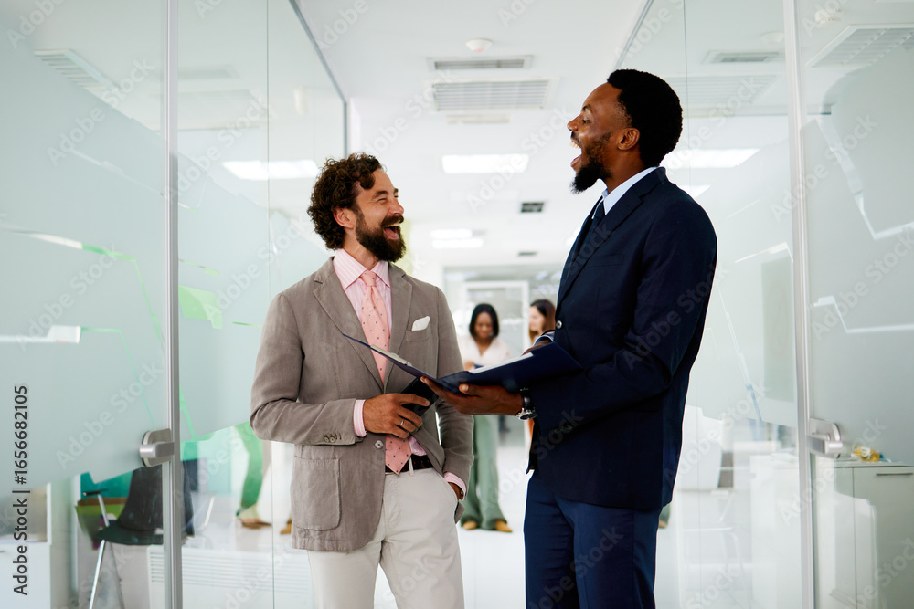 Fototapeta premium Multi-ethnic business people laughing together in modern office corridor