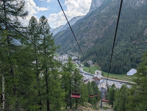 Foto Panoramic view from a chairlift over Gressoney-La-Trinité, Italy, nestled in an Alpine valley with lush forests and majestic mountains in late afternoon