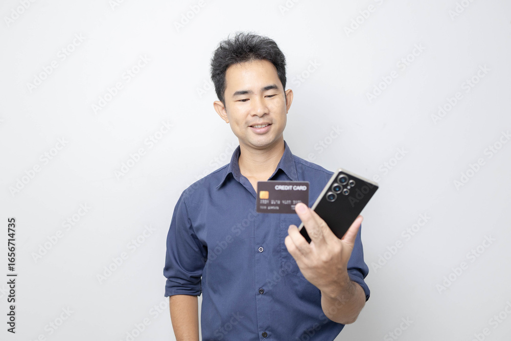 A man stands holding a cell phone, laptop, and credit cards. He is smiling happily and making various gestures for the camera.
A man stands holding a cell phone, laptop, and credit cards. He is smiling happily and making various gestures for the camera.