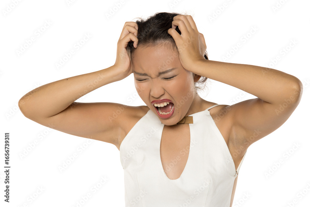 Angry young Kazakh woman screaming and pulling her hair in frustration, studio shot on white background. Angry young Kazakh woman screaming and pulling her hair in frustration, studio shot on white background.
