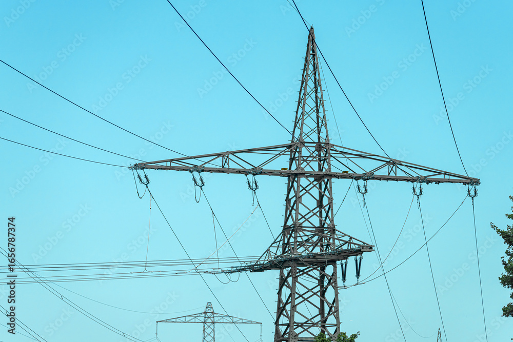 Power transmission tower stands tall against a clear blue sky in the countryside during midday Power transmission tower stands tall against a clear blue sky in the countryside during midday