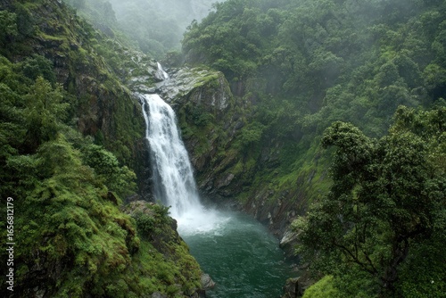 Waterfall cascading into a pool in a lush valley