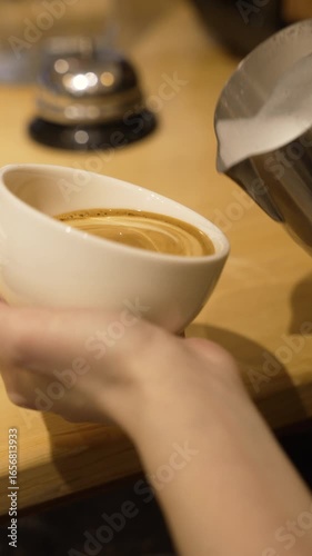 This footage captures the art of pouring steamed milk into a white coffee cup, showcasing the creamy texture and inviting appearance of a freshly made beverage, fa01