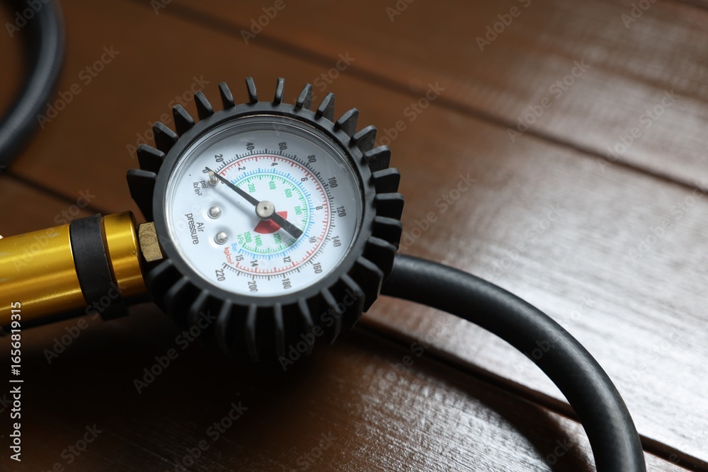 Fototapeta premium One tire inflation gun with gauge on wooden background, closeup