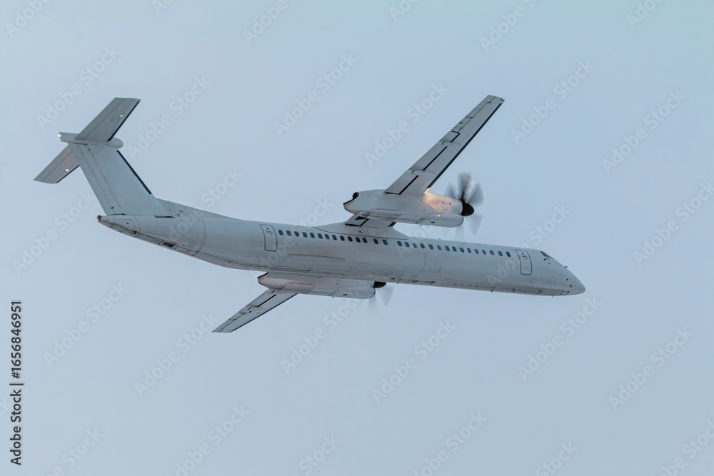 Obraz premium White passenger turboprop airplane flying in the air