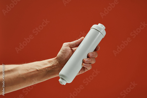 Close-up of a plumber holding a new water filter cartridge, emphasizing the importance of clean water and filtration systems
