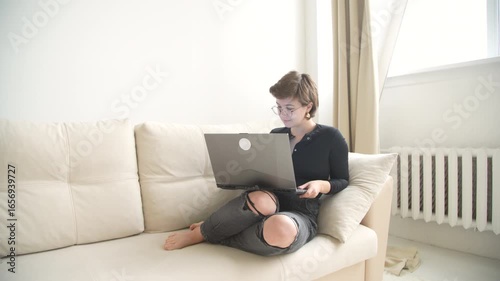 A young female blogger expresses authentic emotions while working on her daily routine - from focused laptop work to joyful phone moments. Perfect for modern lifestyle and digital nomad content