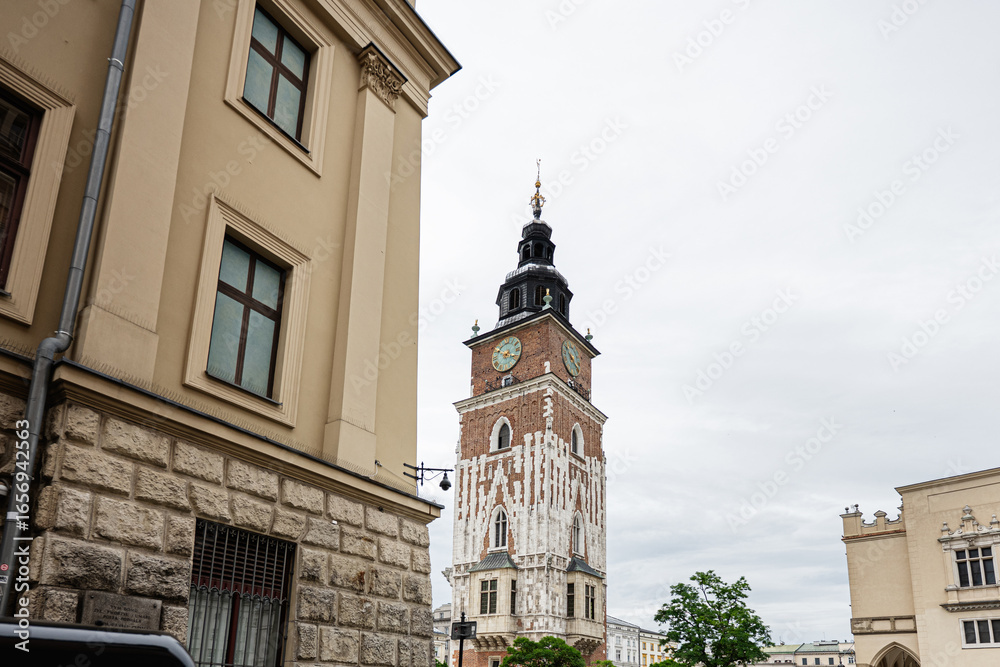 Fototapeta premium Historic street view in Krakow with clock tower and parked cars