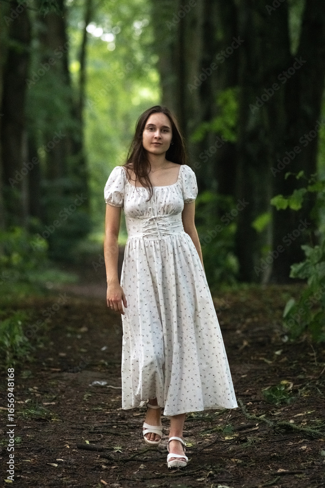 Portrait of a young beautiful dark-haired girl in a summer dress in the park in summer. Portrait of a young beautiful dark-haired girl in a summer dress in the park in summer.