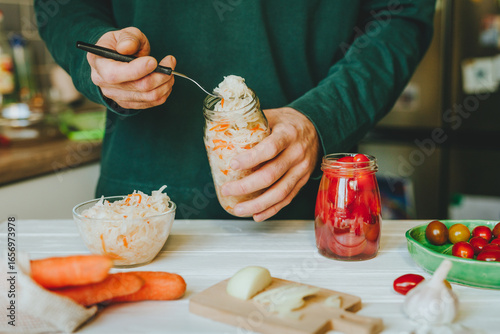 Fotografía Man preparing fermented vegetables in jars on kitchen table