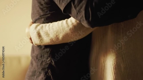 Two people hugging with emotion, torsos visible only.