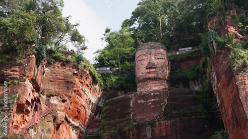 Slow motion centered framing of Buddha’s head and torso with dramatic light and background foliage in Leshan, Sichuan