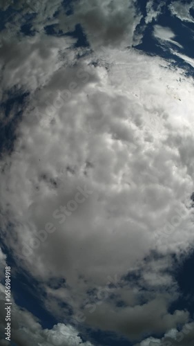 Vertical fisheye view of moving storm clouds in this time lapse. Areas of blue sky

