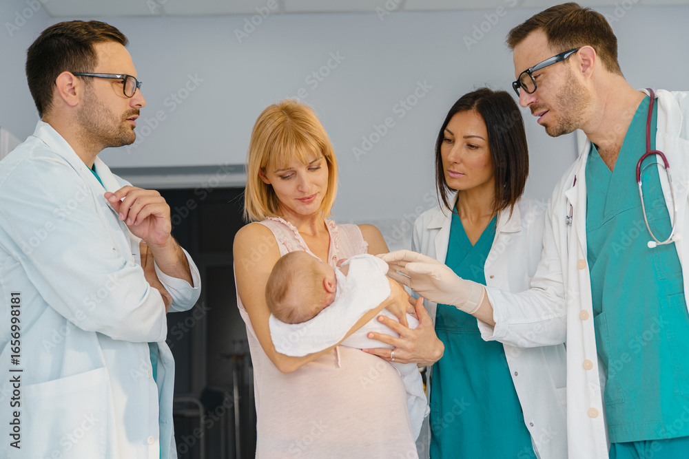 Fototapeta premium New Mom Cradling Baby and Engaging with Medical Team in Bright and Supportive Hospital Environment