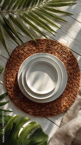 Elegant Table Setting With White Plates on Textured Mat Surrounded by Green L...