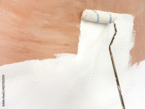 Close up virew of a paint roller being used to coat bare plaster with white primer paint