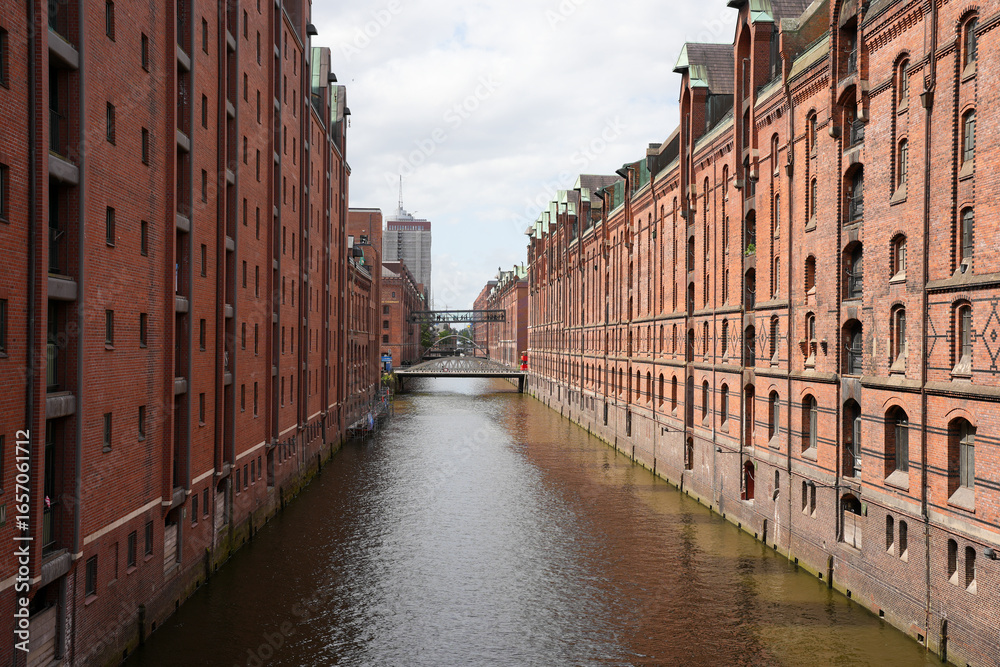Naklejka premium A classic view of a canal in the historic Speicherstadt warehouse district with its red-brick buildings in Hamburg, Germany.
