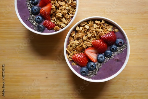 Two Acai Bowls Topped With Granola Strawberries And Blueberries