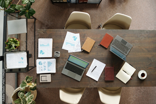 Papier peint Top view showing workspace with two open laptops, printed charts, notebooks, pen