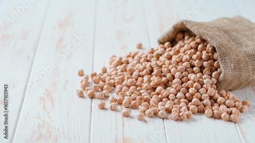 chickpeas in sack on a light kitchen table. Raw chickpeas are scattered out of the bag. Sack of chickpeas spill.
