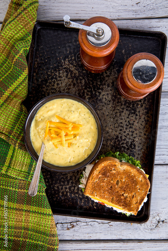 Bowl of cream of broccoli soup with cheese and a whole toasted sandwich