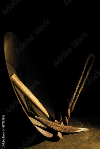 Low key image highlights mining tools including gold pan & hand picks for digging. Handles are wood & hand wrought iron. Gold pan rim is highlighted.