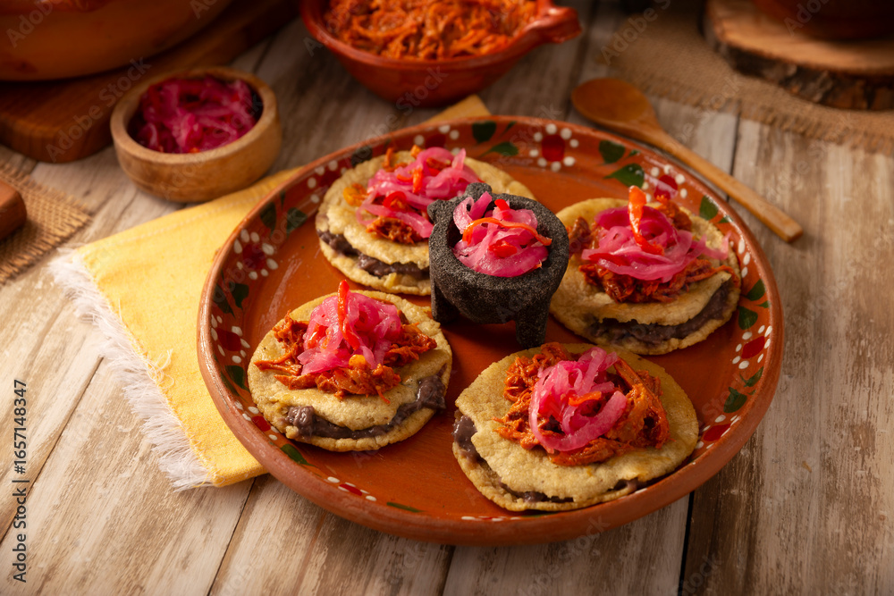 Panuchos, a typical dish from Yucatan, Mexico. A handmade, fried corn tortilla filled with beans, topped with cochinita pibil, pickled red onion, and habanero pepper. Panuchos, a typical dish from Yucatan, Mexico. A handmade, fried corn tortilla filled with beans, topped with cochinita pibil, pickled red onion, and habanero pepper.