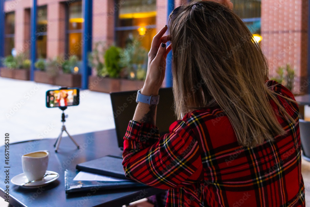 Fototapeta premium Influencer recording video blog outdoors, using smartphone and tripod