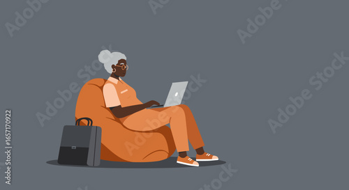 An older Black woman comfortably works on her laptop from a bean bag chair, illustrating remote work, online learning, or modern senior lifestyle and entrepreneurship.