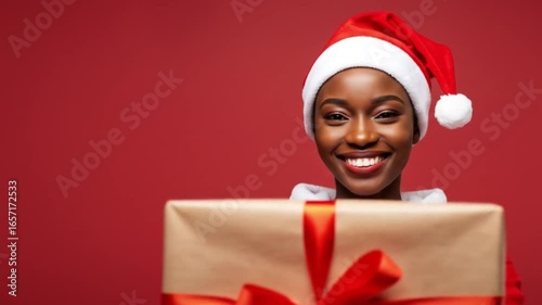 Woman dressed as Santa holds a wrapped Christmas gift with a red ribbon.