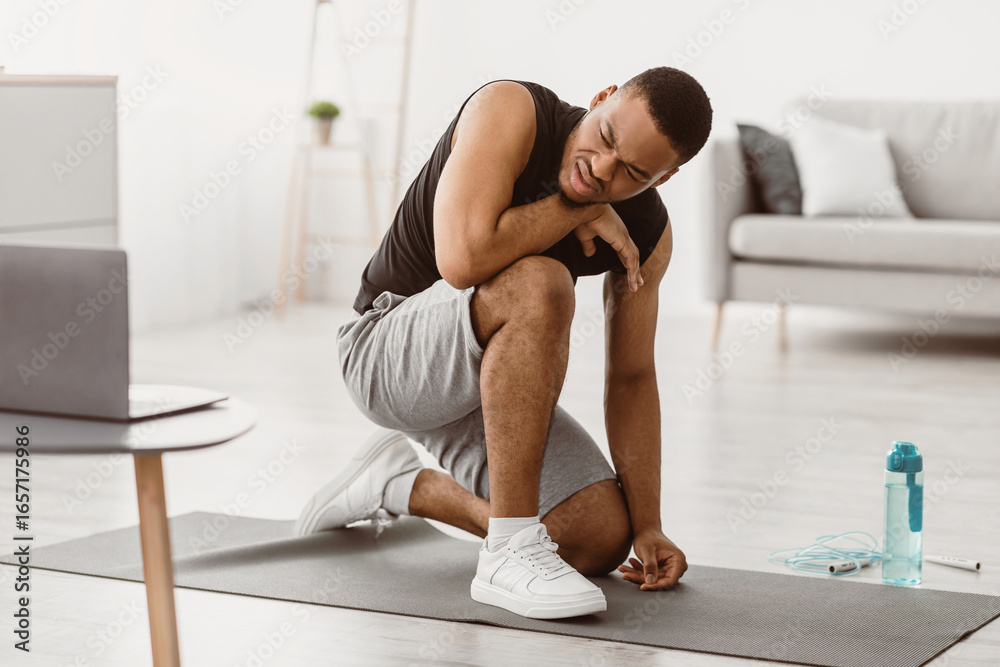 Fototapeta premium Fitness Burnout. Exhausted African American Guy Tired Of Online Workout Exercising At Laptop Sitting On Floor At Home. Beginner Resting After Difficult Exercise Concept. Selective Focus