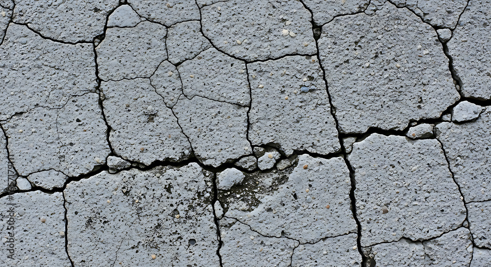 Fototapeta premium Cracked concrete texture background with detailed fissures, perfect for design and grunge themes