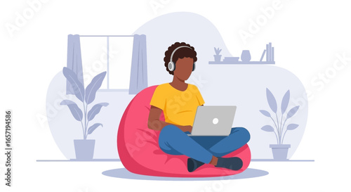 Young person comfortably working or studying remotely on a laptop with headphones at home. Ideal for online learning, telecommuting, and digital lifestyle concepts.