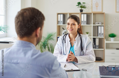 Bild auf Leinwand Friendly female doctor sitting at her desk with male patient