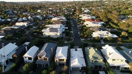 High-angle perspective of a densely packed residential area, with rooftops and green trees casting long shadows during a beautiful sunrise or sunset.