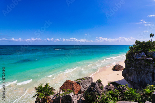 Fototapeta Naklejka Na Ścianę i Meble -  Magnificent sea views of the brilliant blue green waters of the Caribbean Sea with a viewing deck leading to the playa ruinas, or ruins beach at the late 13th century Mayan ruins of Tulum,Mexico