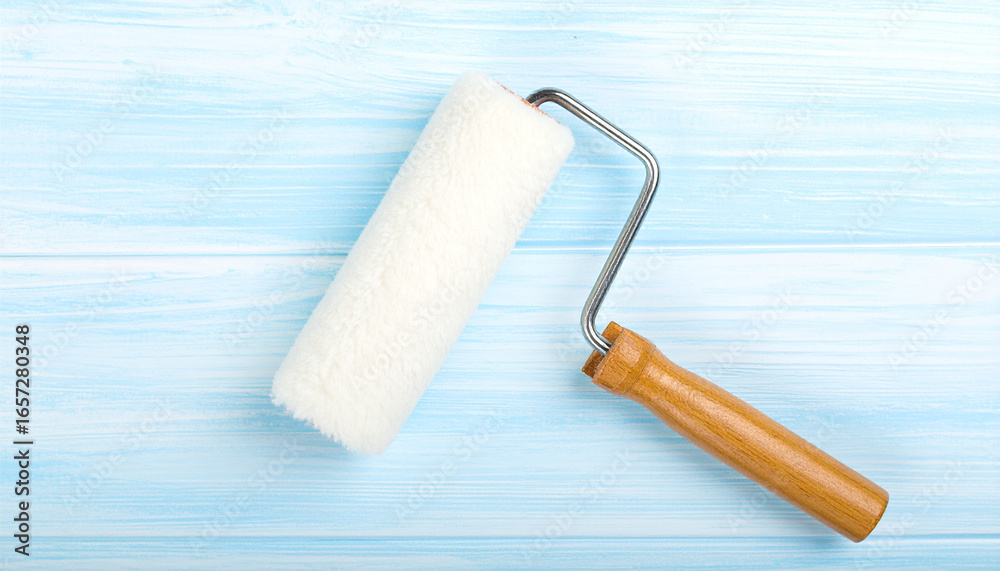 Fototapeta premium Paint Roller on Blue Surface: A clean paint roller rests casually on a soothing blue surface, perfect for renovation, painting, and design themes.
