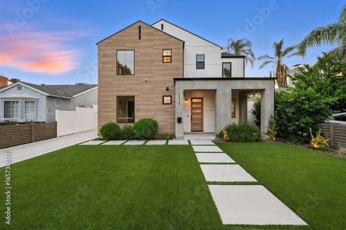 Carta da parati Modern suburban house with manicured lawn at sunset.