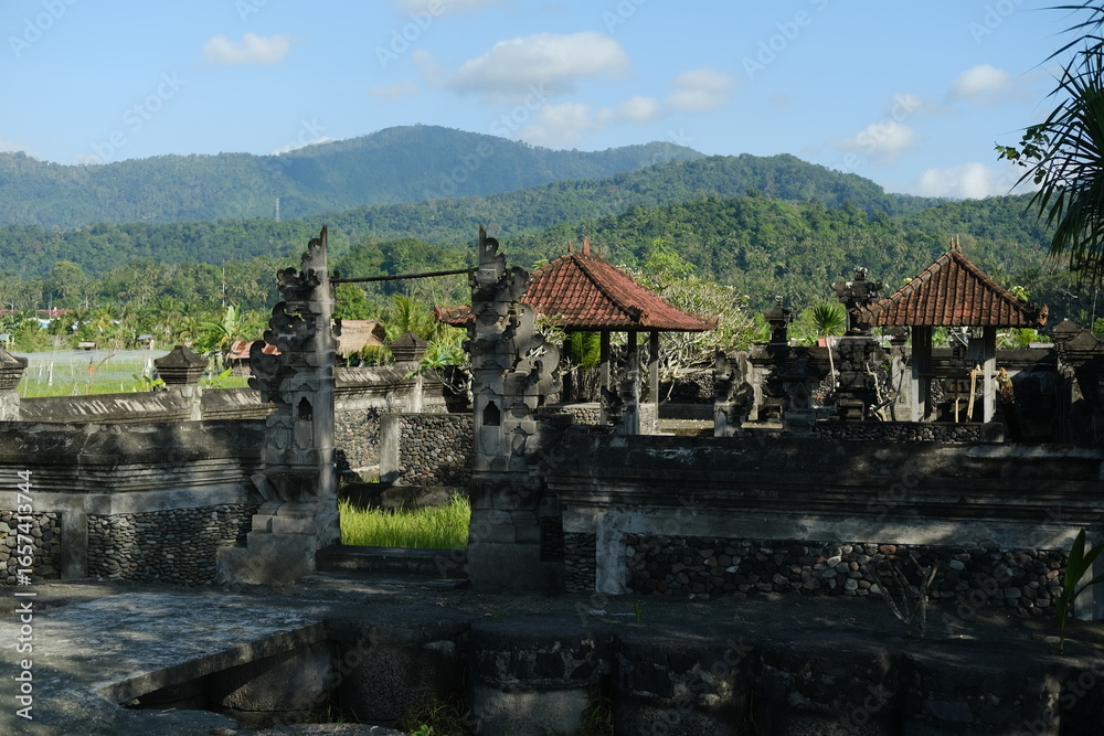 Traditional Balinese Stone Home Temple with Tiled Roof Against Mountains Traditional Balinese Stone Home Temple with Tiled Roof Against Mountains